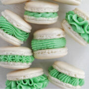 white shelled macarons with green buttercream frosting.