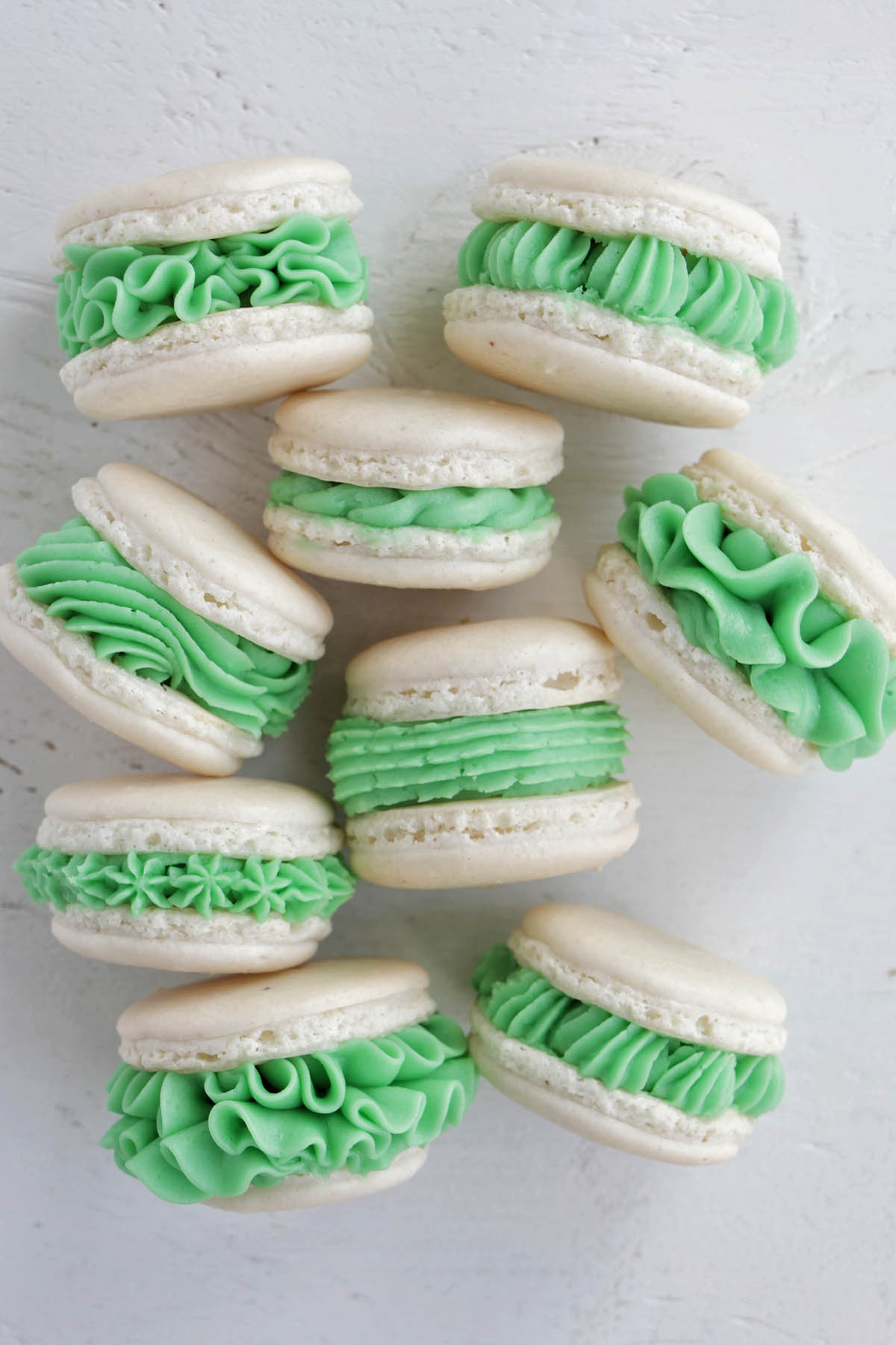 white macaron shells with light green frosting.