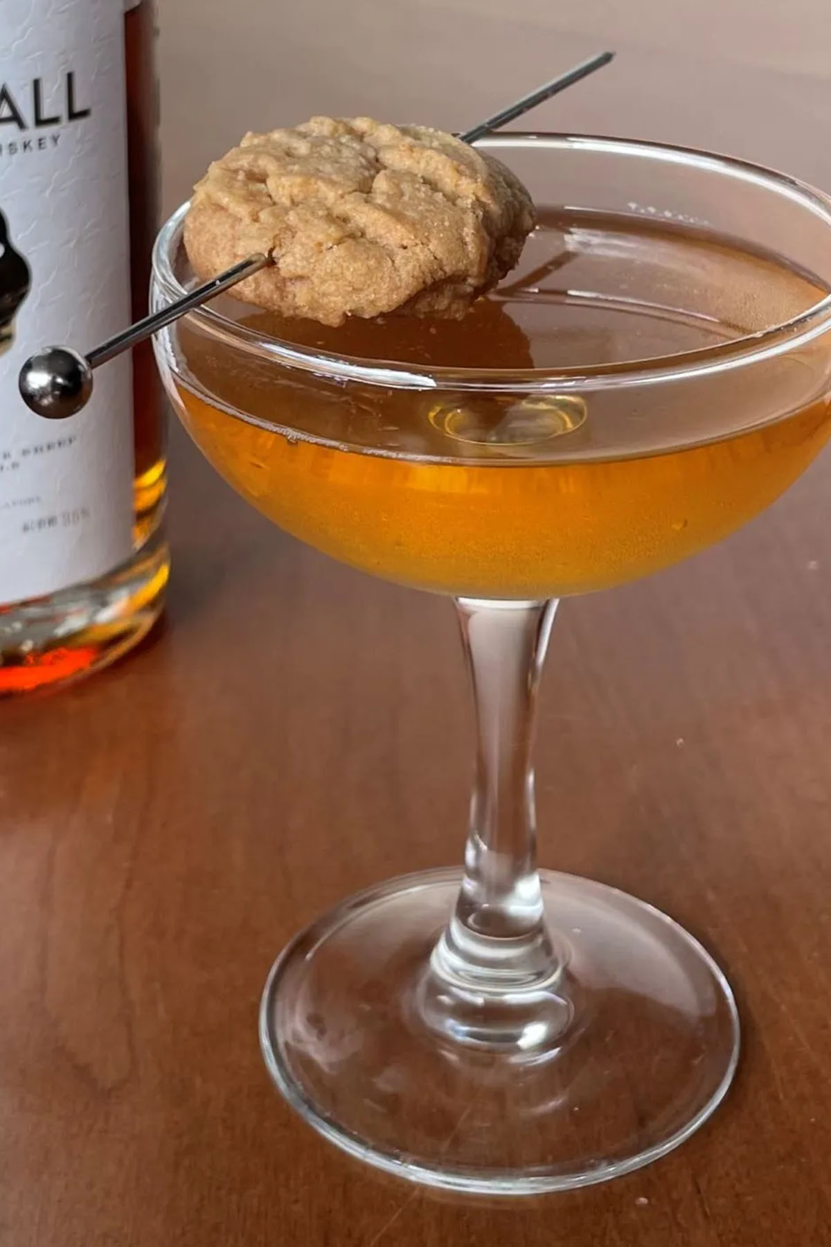 peanut butter whiskey cocktail in a couple glass garnished with a cookie.
