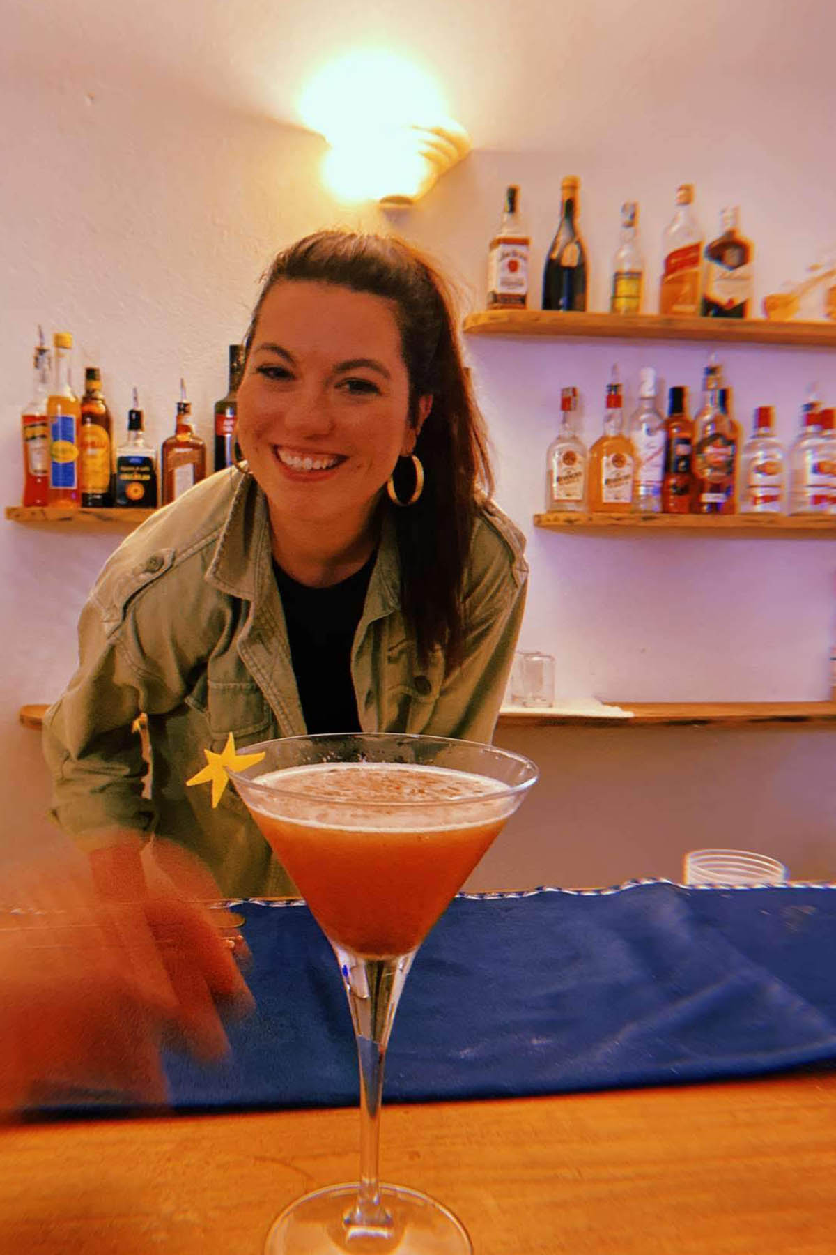 girl smiling next to a fruity martini.