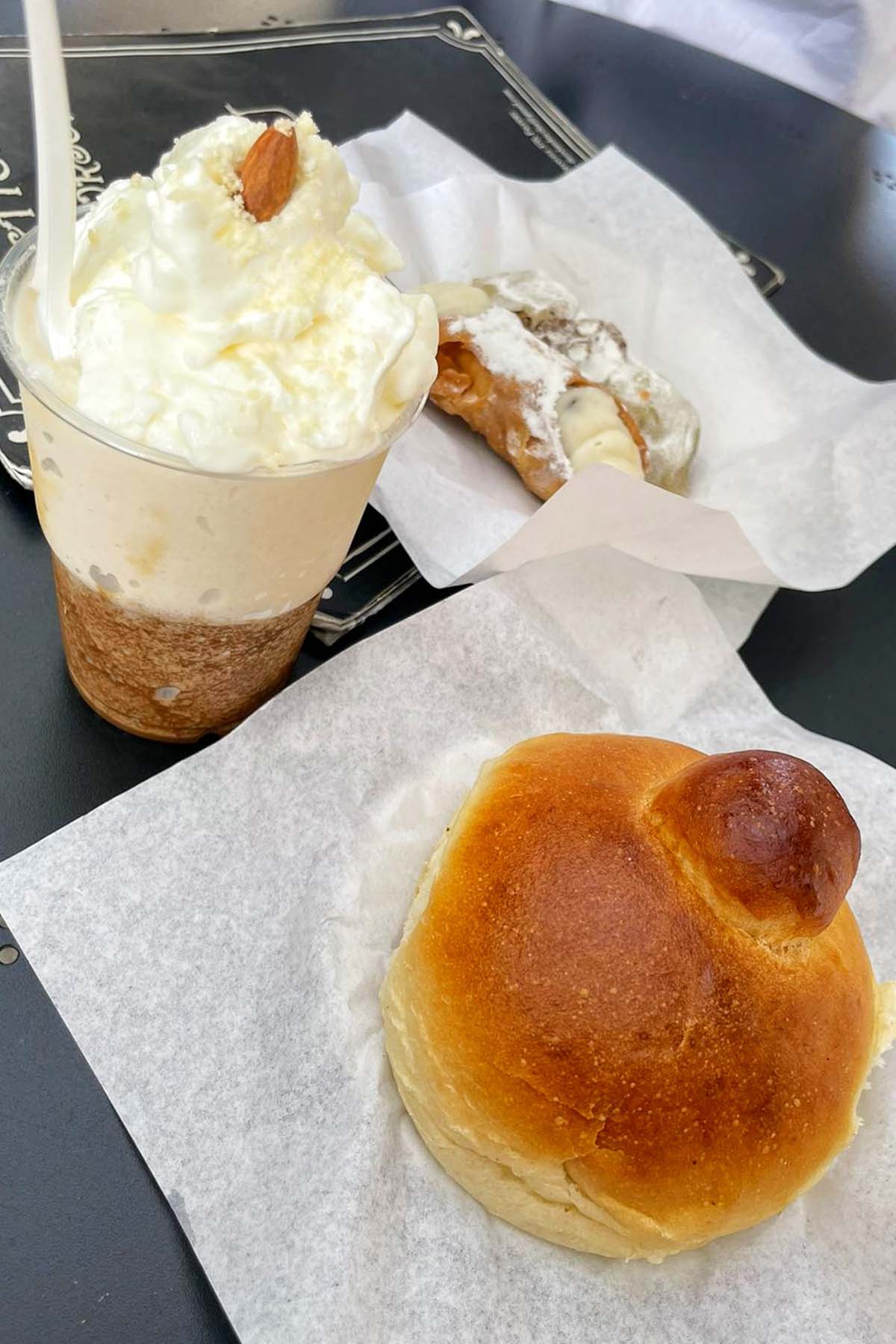 granita sitting next to brioche bun and cannoli.