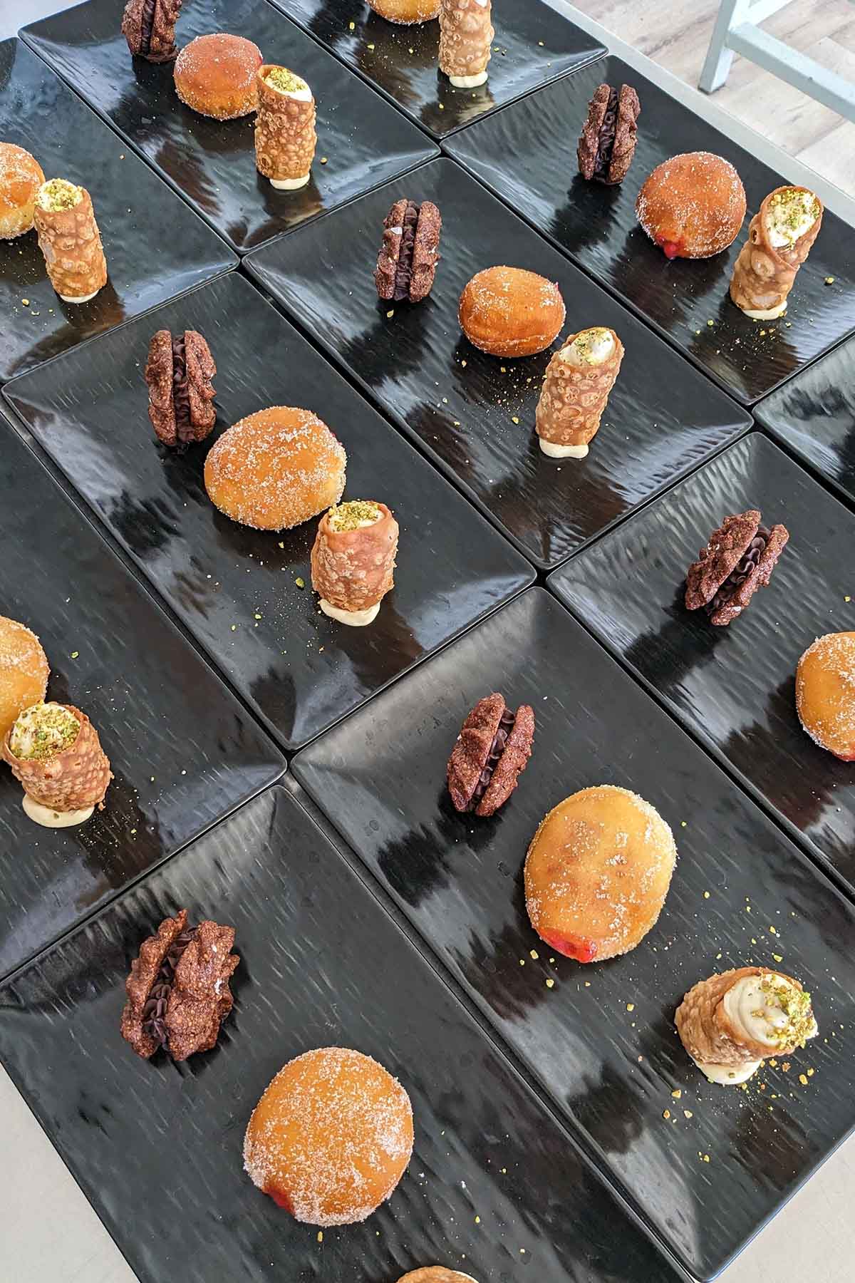 black square plates lined on a table filled with desserts.
