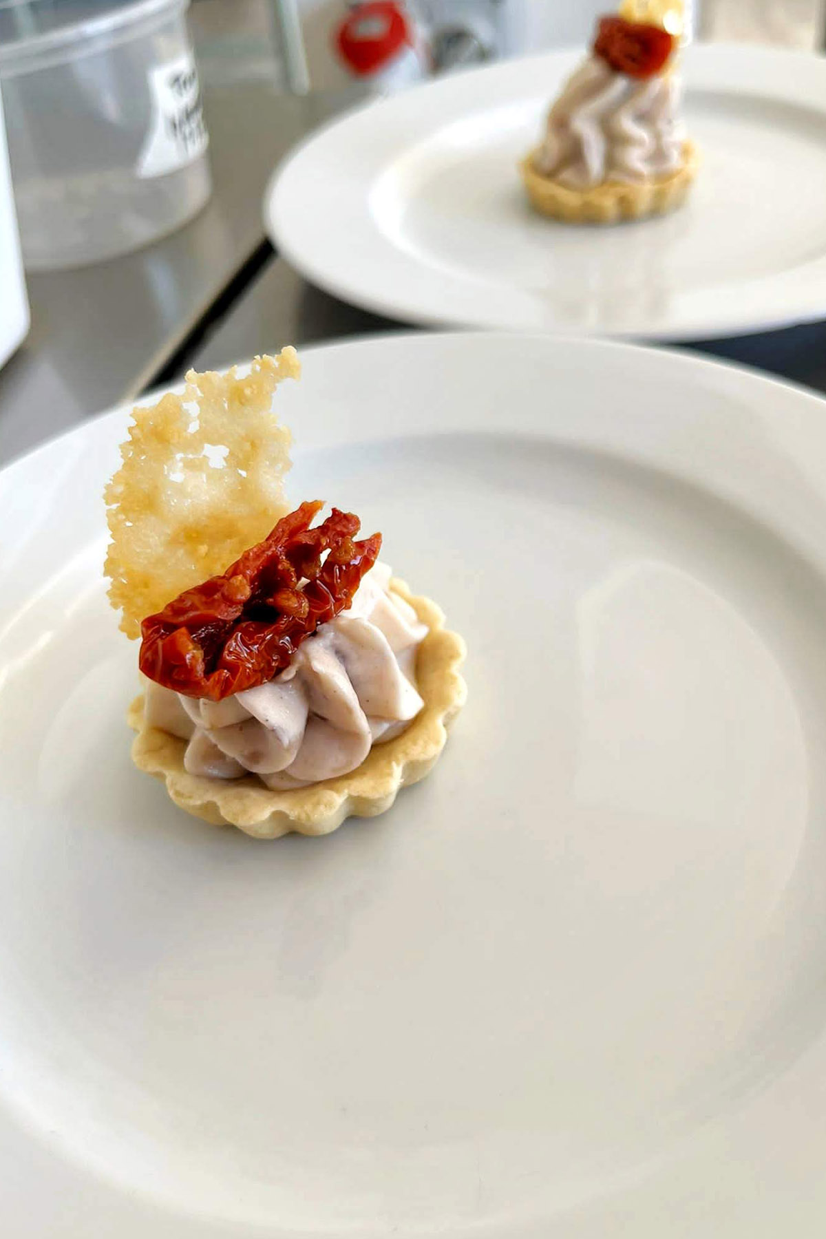 mini tart appetizer bite with ricotta mousse and sun dried tomato.