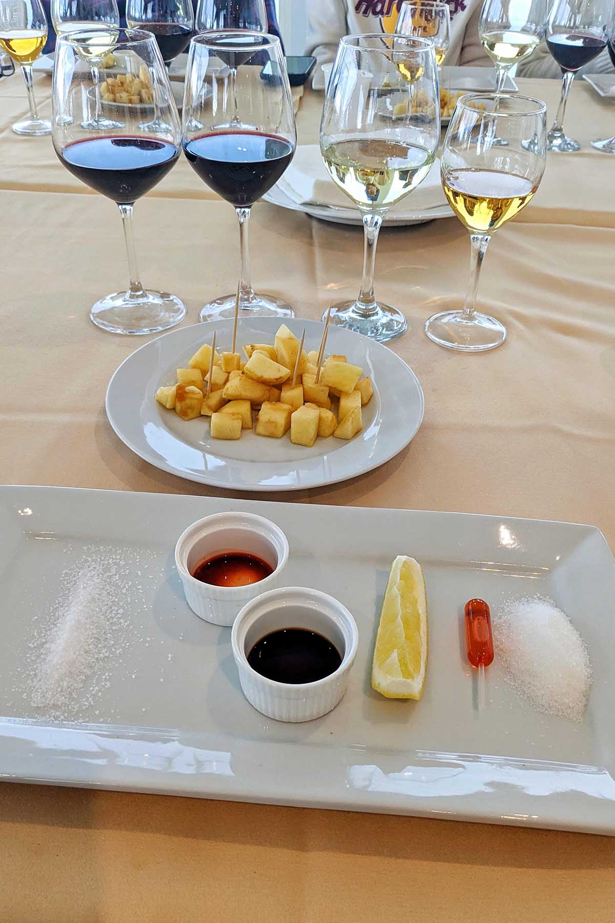 four wine glasses next to a plate of apples and food tastings.