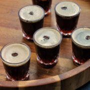 espresso martini shots on a wooden tray.