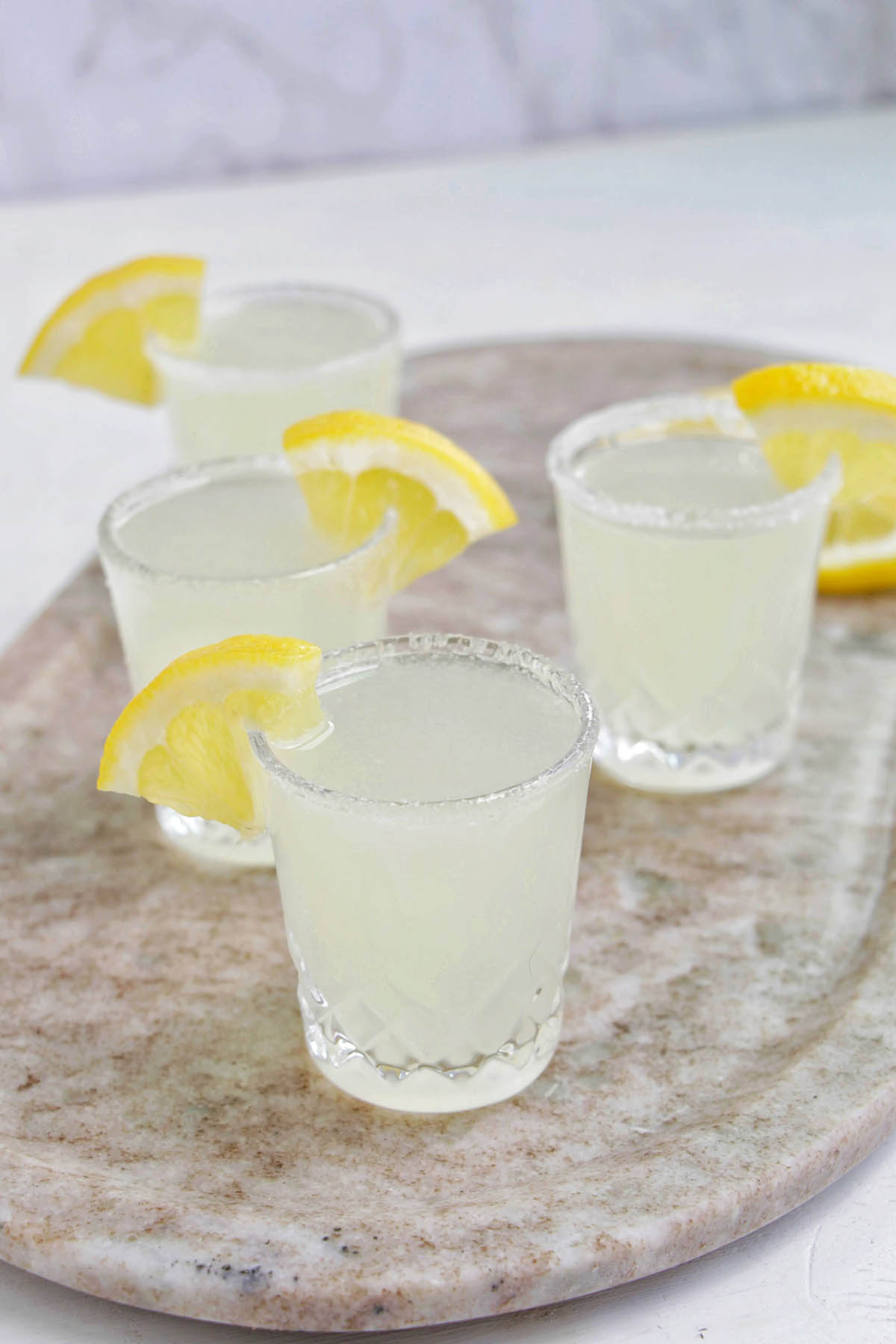four lemon drop shots on a serving tray.