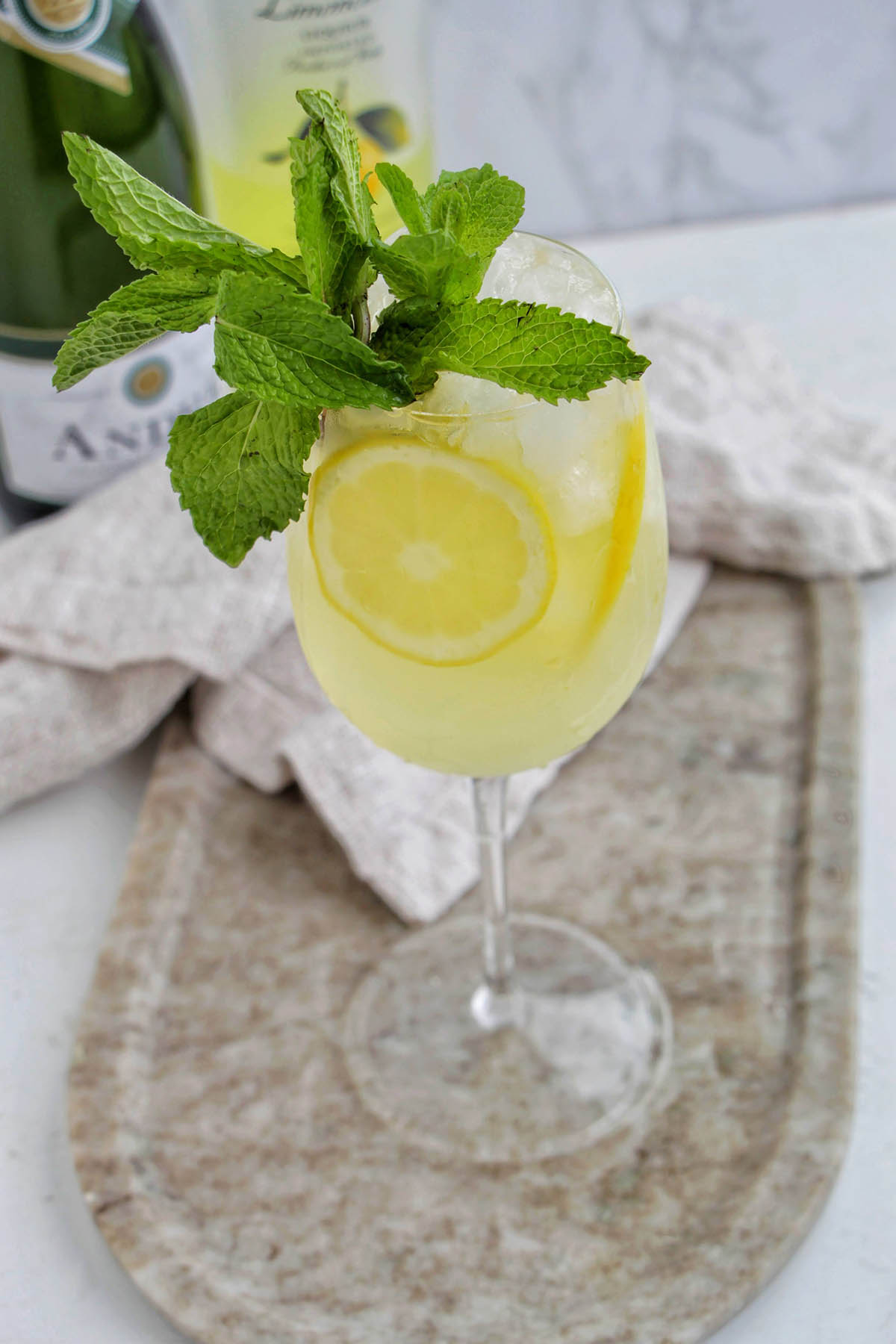 limoncello spritz cocktail in a wine glass with a mint garnish.