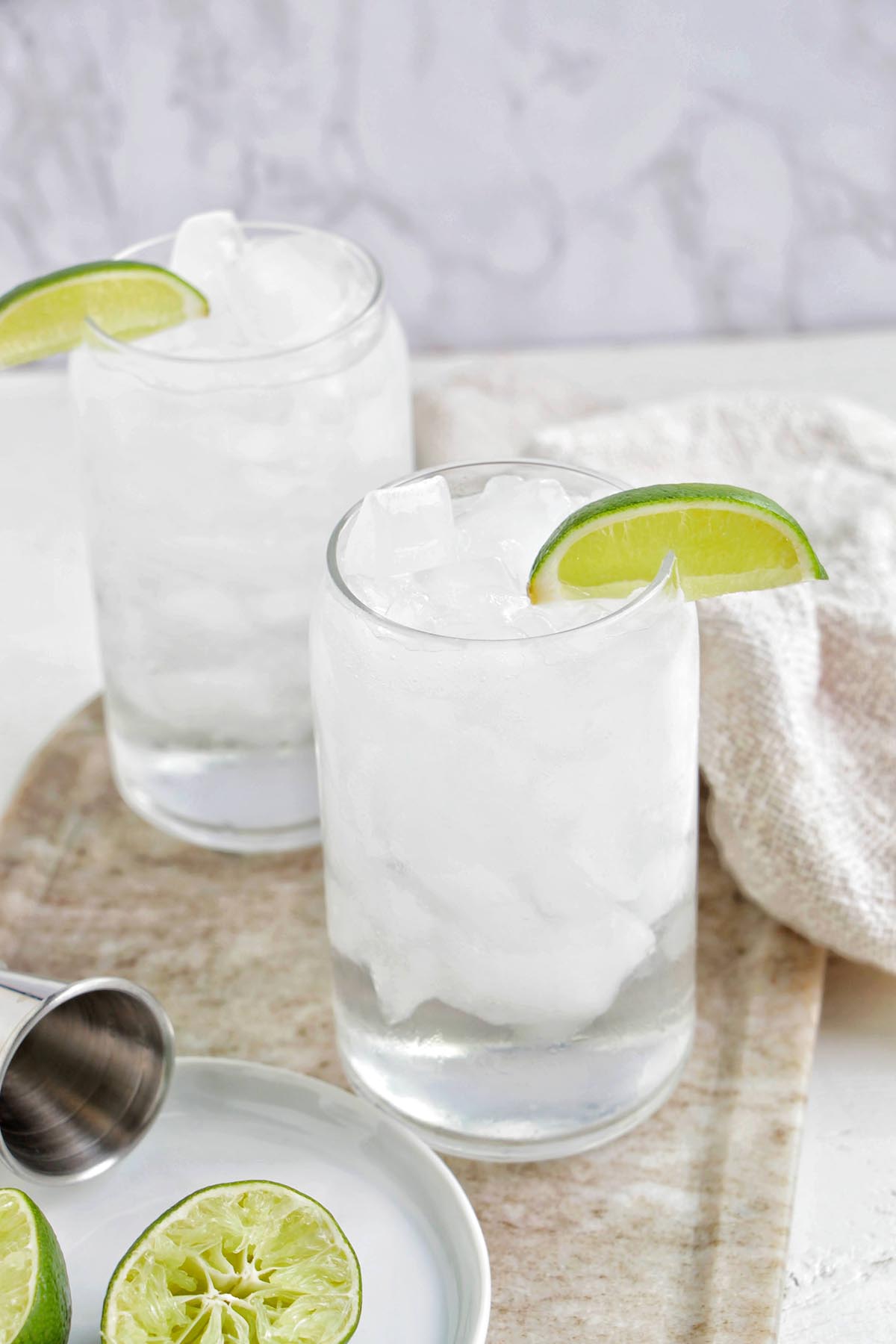 two glasses of tequila soda garnished with lime wedge.