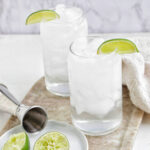 two glasses of tequila soda garnished with lime wedge.