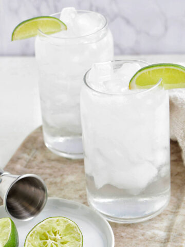 two glasses of tequila soda garnished with lime wedge.