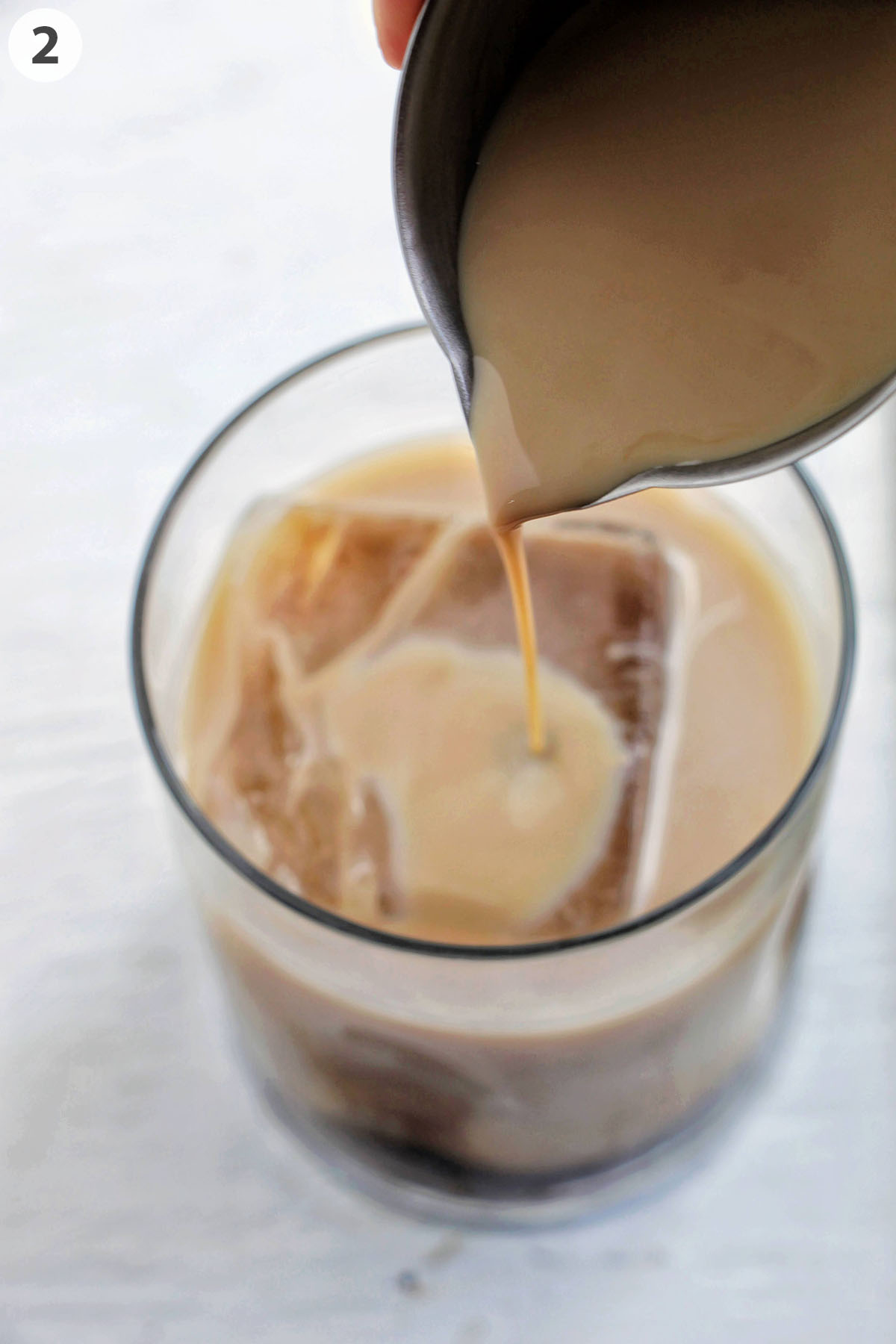 numbered photo pouring Baileys Irish cream into a lowball cocktail glass.
