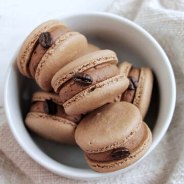 chocolate macarons with chocolate buttercream and an espresso bean garnish.