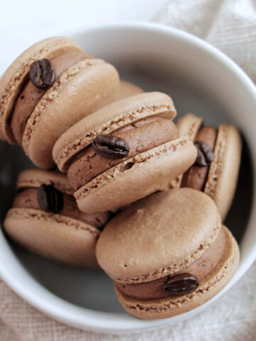 chocolate macarons with chocolate buttercream and an espresso bean garnish.