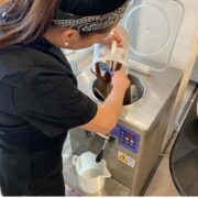 girl pouring chocolate gelato into a gelato machine.
