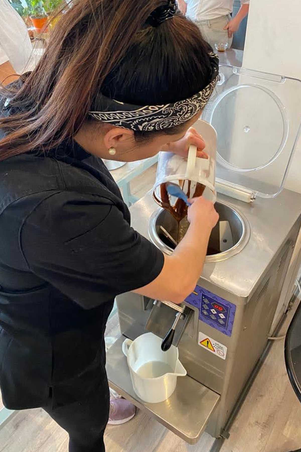 girl pouring chocolate gelato into a gelato machine.