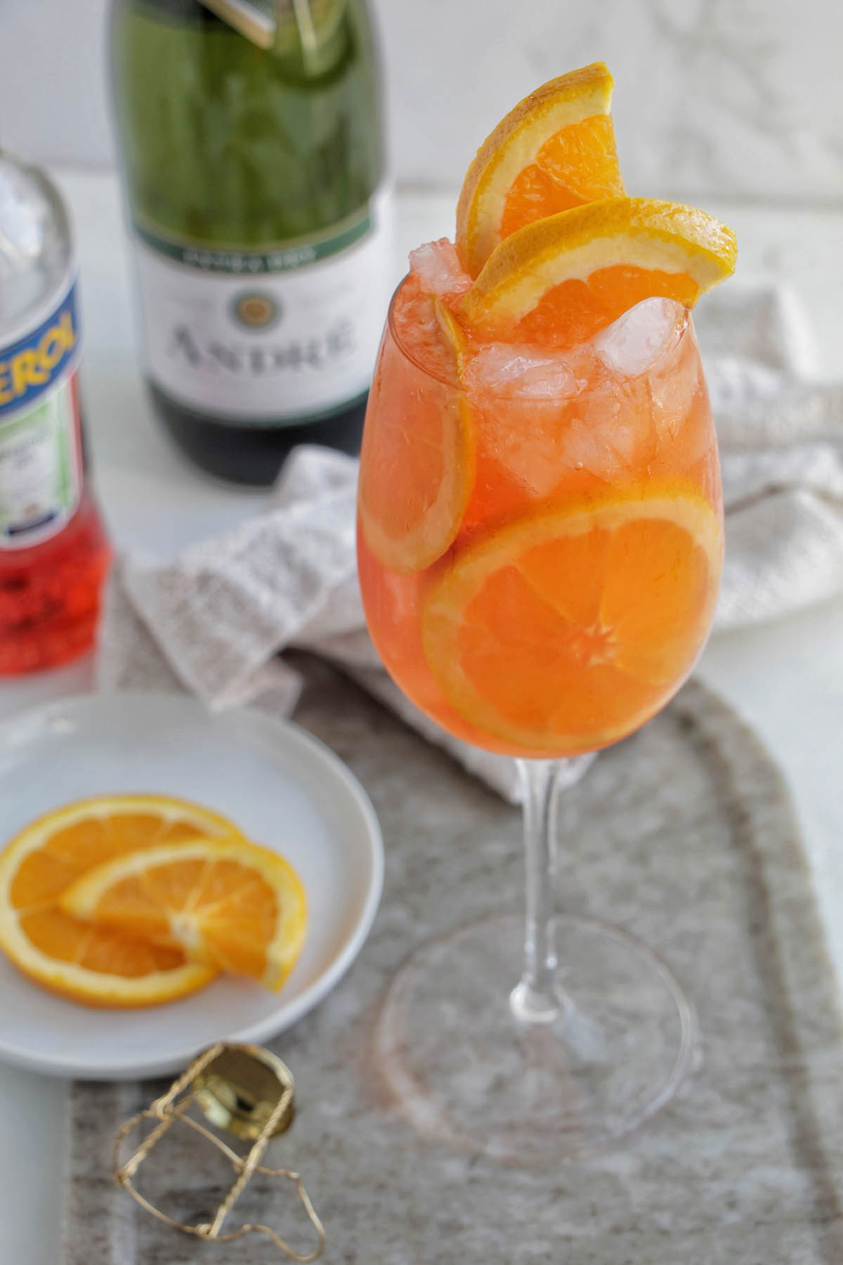 Aperol spritz cocktail in a wine glass with orange garnish.