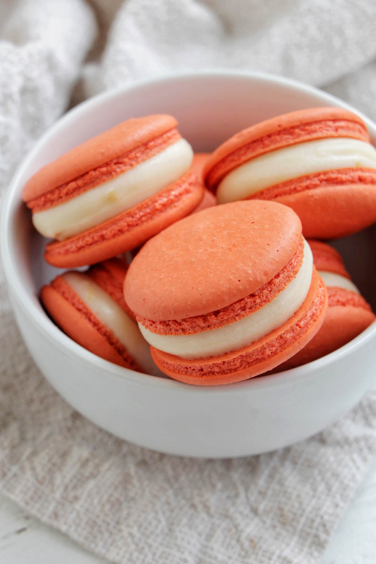 orange macarons filled with ganache in a small bowl.
