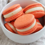 orange macarons in a bowl.
