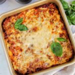Italian lasagna in a pan garnished with basil.