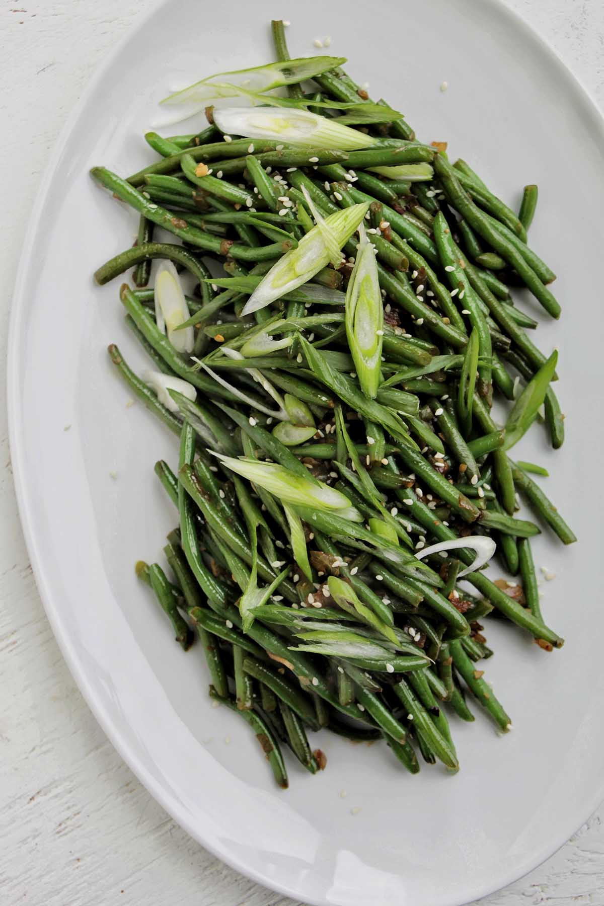 sautéed green beans garnished with green onions and sesame seeds.