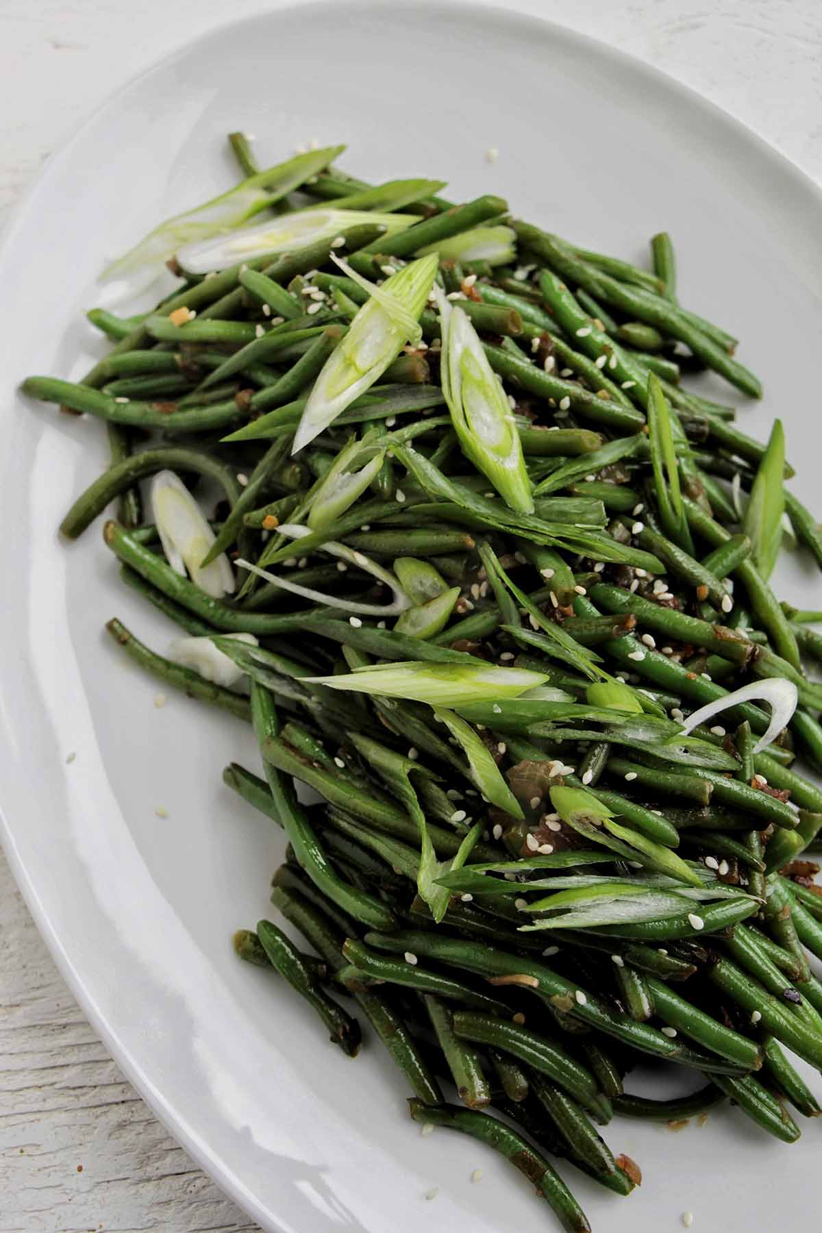 sautéed green beans garnished with green onions and sesame seeds.