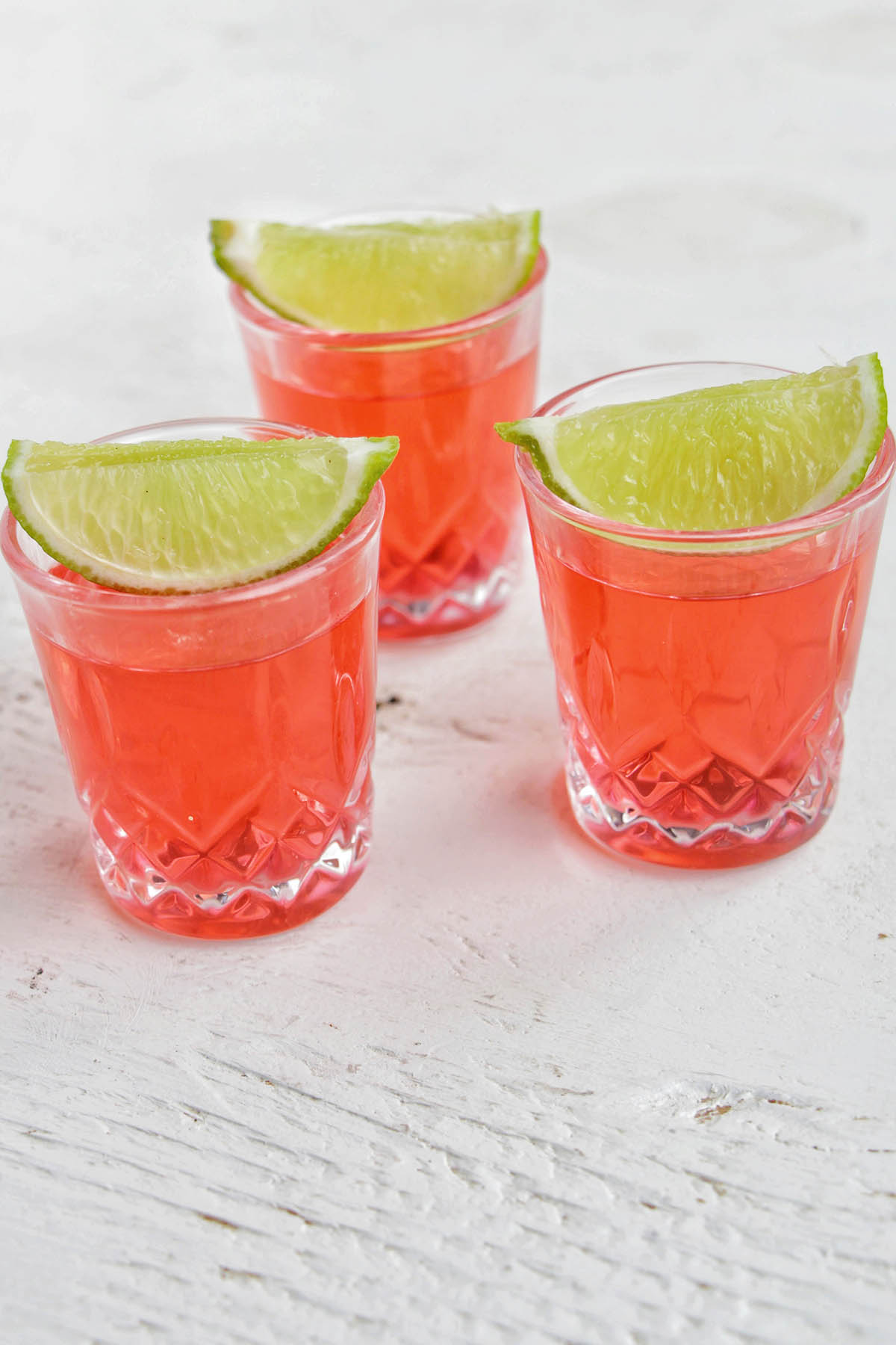 three pink shots garnished with a lime.