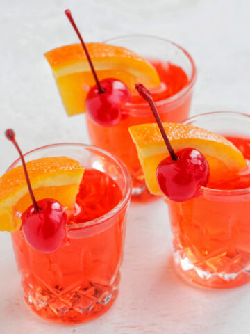 three red shots garnished with orange and cherry.