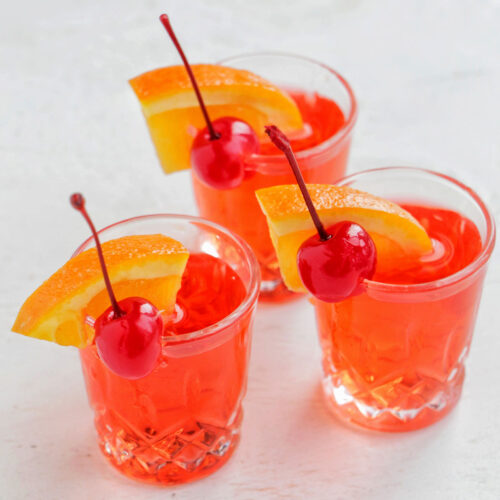 three red shots garnished with orange and cherry.