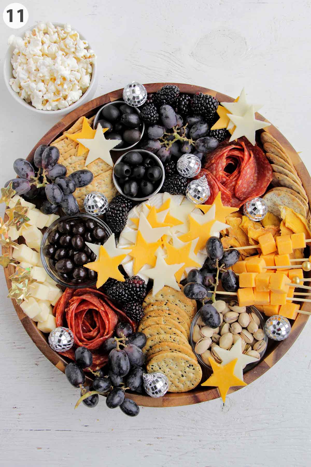 numbered photo showing how to garnish a cheese board with disco ball ornaments and star shaped cheese.