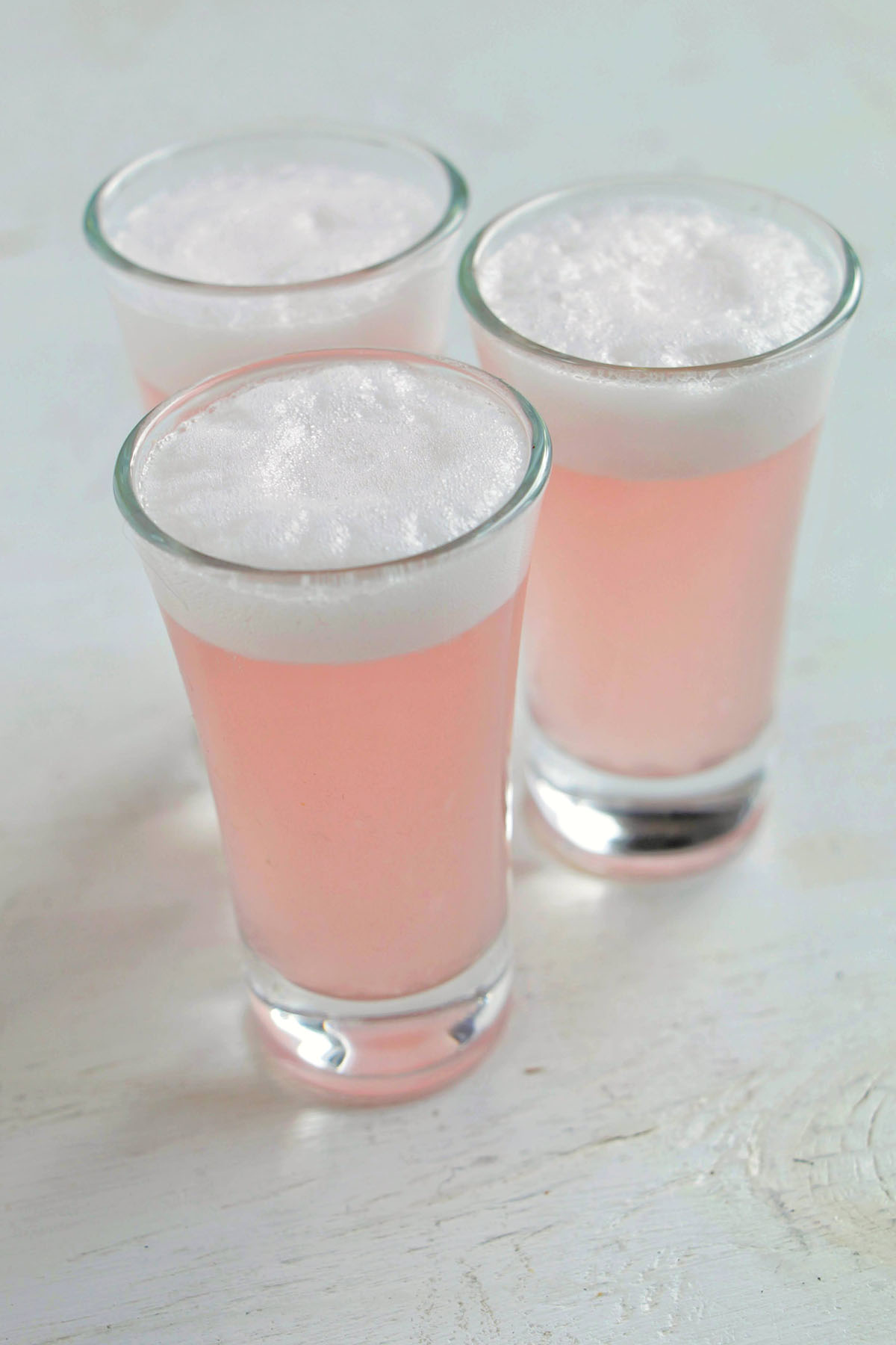 three clover club shots with egg white tops.