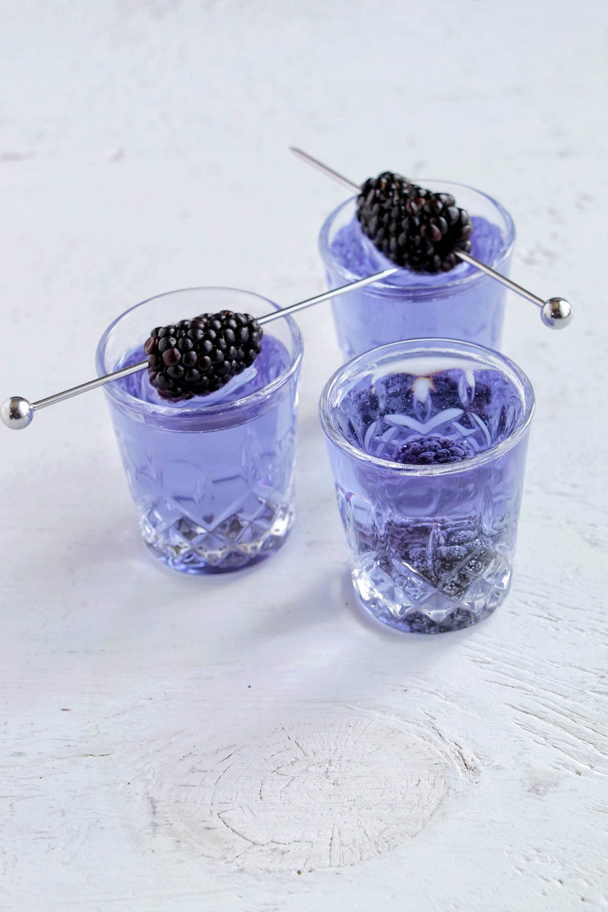 three empress gin and tonic shots with blackberry garnish.