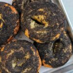 poppy seed bagels on sheet tray.