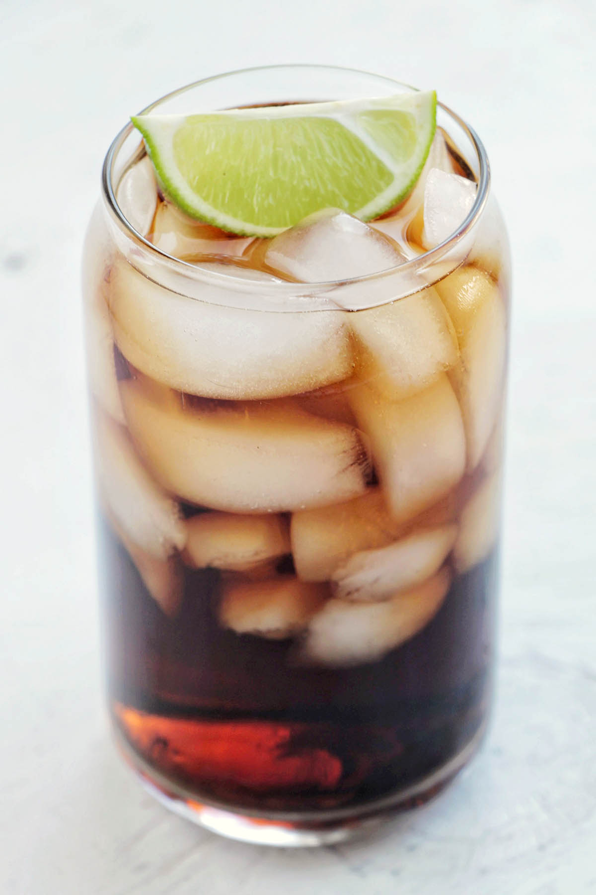 rum and coke drink with lime garnish.