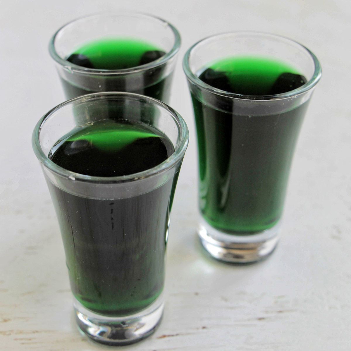 three green shots in clear shot glasses.