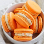 orange carrot cake macarons in a bowl.