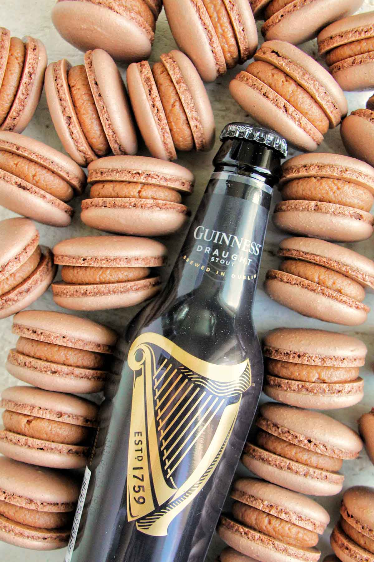 chocolate Guinness macarons next to a Guinness beer bottle.