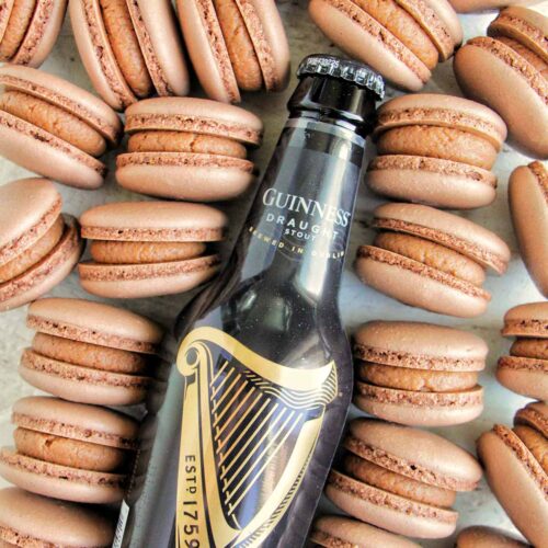 chocolate Guinness macarons next to a Guinness beer bottle.