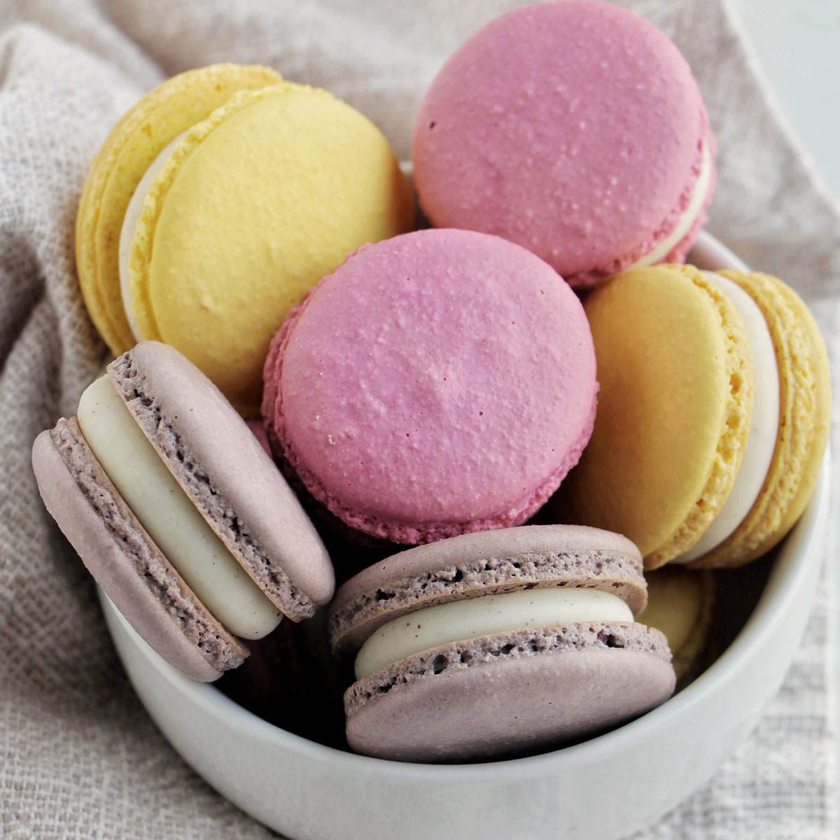 pastel colored macaron shells in a bowl.