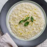 plated parmesan risotto garnished with basil and cheese.