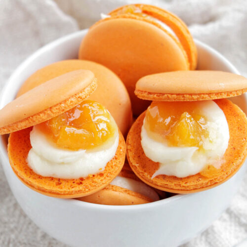 peach macarons in a bowl.