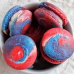 red, white, and blue tie dye macarons in a bowl.