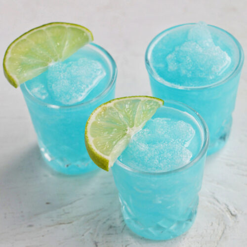 three frozen blue shots with lime garnish.
