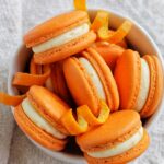 orange creamsicle macarons in a bowl.