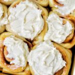 frosted cinnamon rolls in a pan.