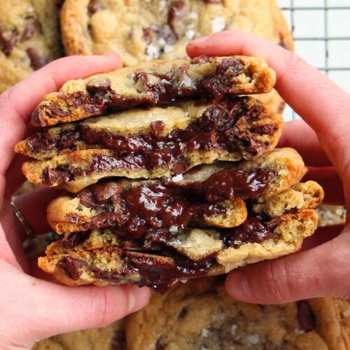 hands holding hot fudge filled chocolate chip cookies.