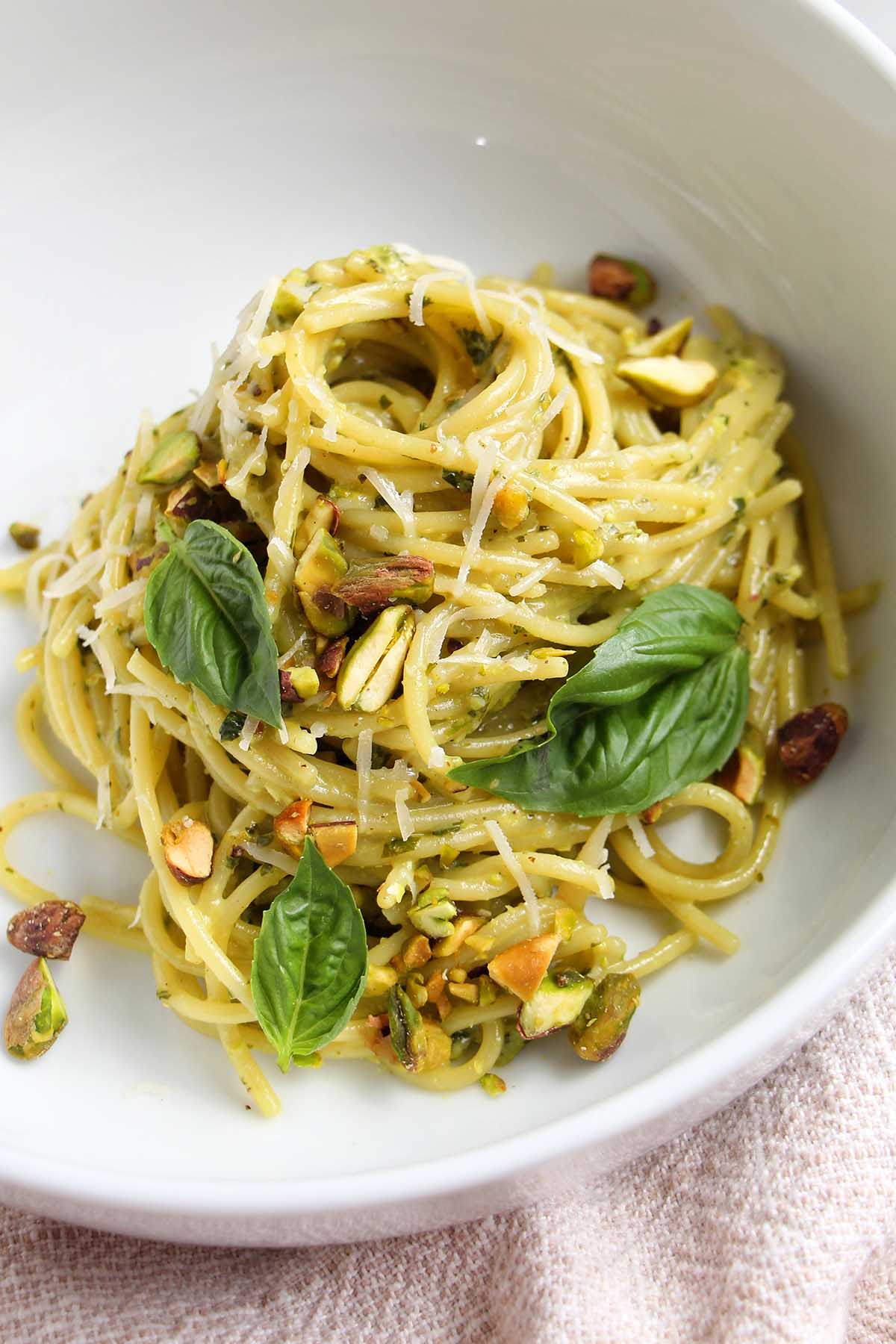 bowl of pistachio pesto pasta with basil garnish.