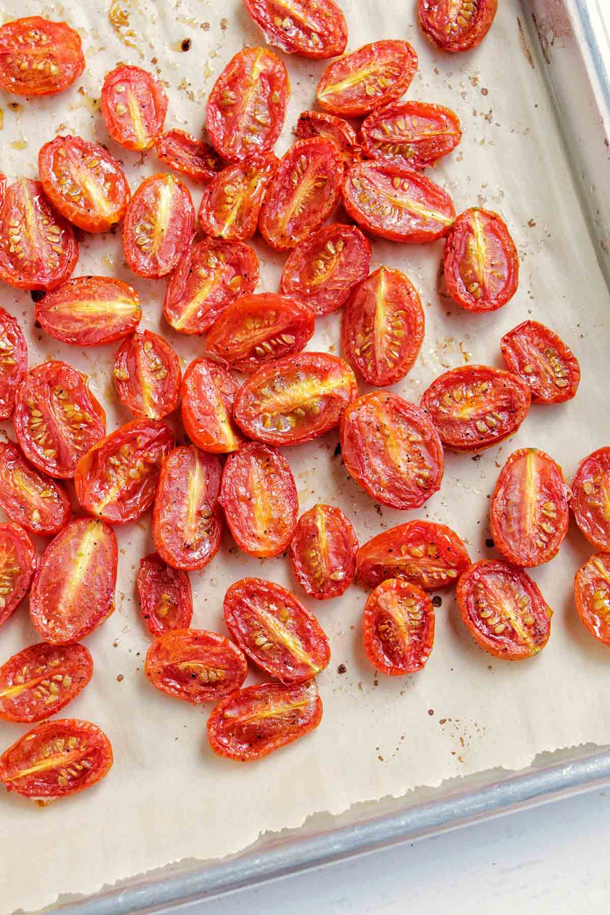 candied cherry tomatoes on a parchment lined sheet tray.