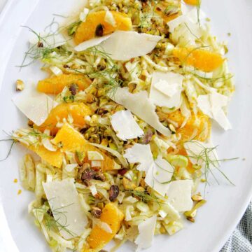 shaved fennel salad topped with orange slices, parmesan, and pistachios.