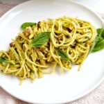 plate of pistachio pesto pasta with basil garnish.