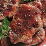 slice of pork scallopini with red wine sauce and cracked pepper.